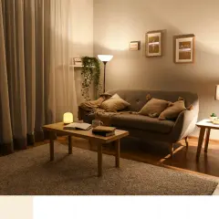 Przytulny salon z sofą, stolikiem kawowym i lampami. Dominują **ciepłe kolory**, tworząc relaksującą atmosferę.