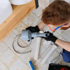 Hydraulik z przepychaczem rur przy umywalce.