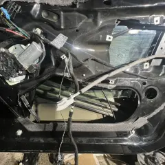 Wnętrze drzwi BMW E46 z widocznym mechanizmem podnoszenia szyby i przewodami.