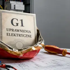 Certyfikat "G1 Uprawnienia Elektryczne" w paczce chipsów, obok multimetru i śrubokręta.