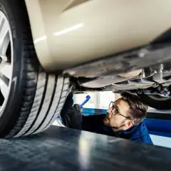 Mechanik sprawdza podwozie auta, szukając informacji o wymiana amortyzatorów cena.