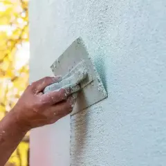 Ręka fachowca wygładza tynk silikonowy. Czas na zacarcie tynku zależy od warunków, ale efekt końcowy jest piękny.