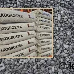 Stos worków z napisem "EKOGROSZEK" na tle węgla. Sprawdź aktualną eko groszek cena i wybierz najlepszą ofertę.