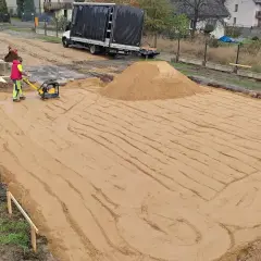 Pracownik zagęszcza piasek zagęszczarką. Trwają prace ziemne, ustalana jest korytowanie cena za m2.