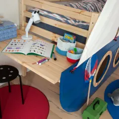 Biurko z łóżkiem w kształcie statku, z zabawkami i książką do nauki.