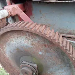Zardzewiałe koło zębate i mechanizm posuwu rozrzutnika obornika.