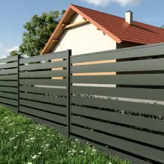 Nowoczesny montaż ogrodzenia panelowego cena. Elegancka szara siatka z drewnianymi wstawkami otacza dom z czerwonym dachem.