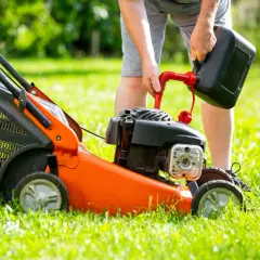 Mężczyzna nalewa paliwo do kosiarki. Zastanawiasz się, jakie paliwo do kosiarki będzie najlepsze?
