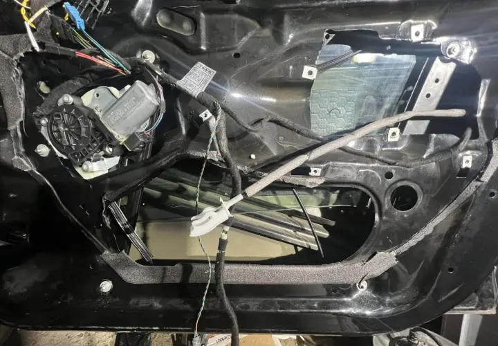 Wnętrze drzwi BMW E46 z widocznym mechanizmem podnoszenia szyby i przewodami.
