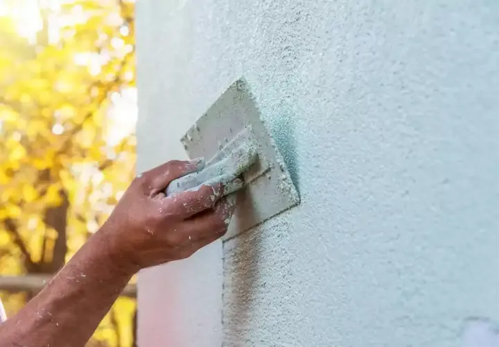 Ręka fachowca wygładza tynk silikonowy. Czas na zacarcie tynku zależy od warunków, ale efekt końcowy jest piękny.