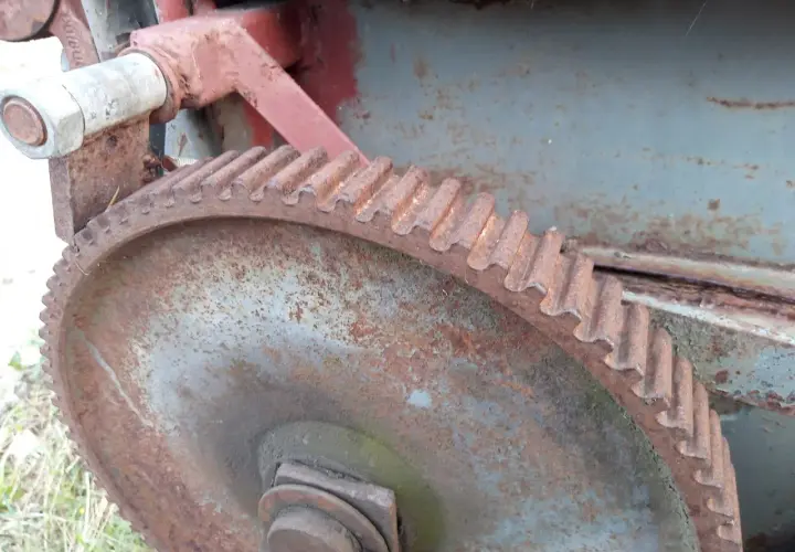 Zardzewiałe koło zębate i mechanizm posuwu rozrzutnika obornika.