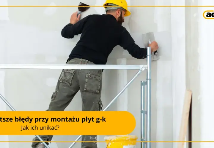 Fachowiec w żółtym kasku i roboczych spodniach pracuje na rusztowaniu, nakładając gładź na ścianę. To praca przy **suchej zabudowie**.