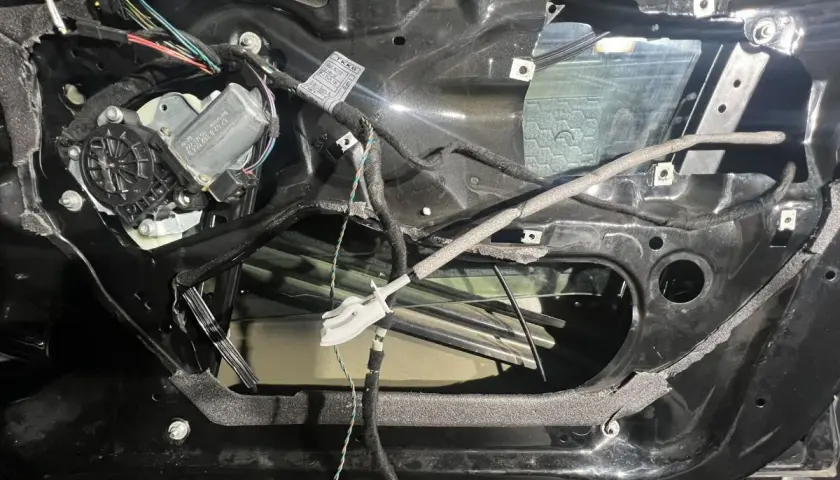 Wnętrze drzwi BMW E46 z widocznym mechanizmem podnoszenia szyby i przewodami.