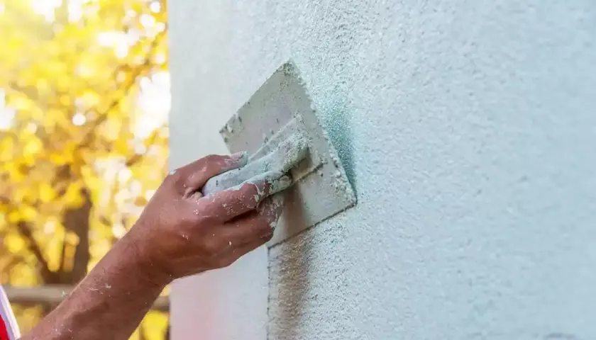Ręka fachowca wygładza tynk silikonowy. Czas na zacarcie tynku zależy od warunków, ale efekt końcowy jest piękny.