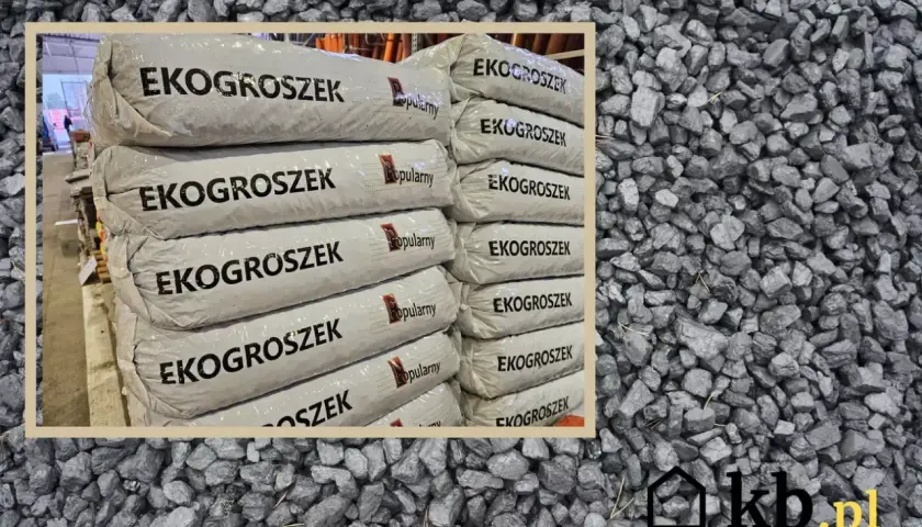 Stos worków z napisem "EKOGROSZEK" na tle węgla. Sprawdź aktualną eko groszek cena i wybierz najlepszą ofertę.