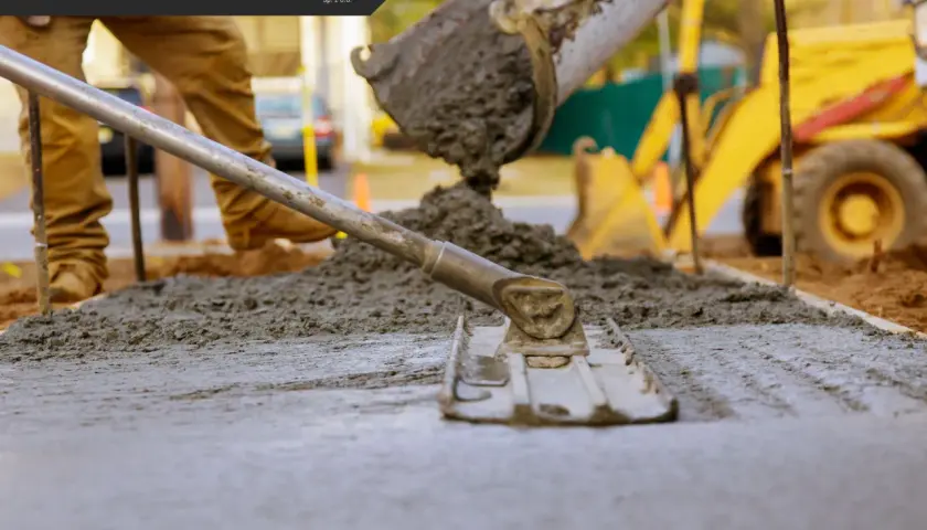 Pracownik wylewa beton, używając narzędzi do jego wyrównania. Różne rodzaje betonu wymagają specyficznych metod aplikacji.