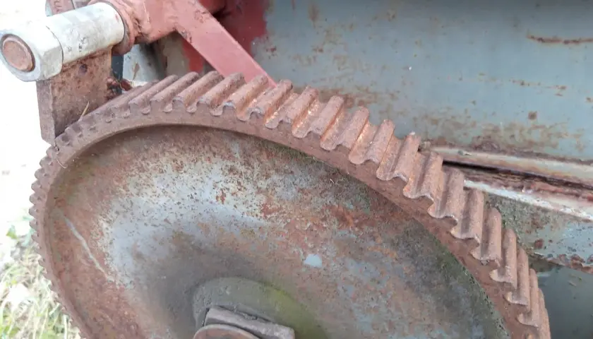Zardzewiałe koło zębate i mechanizm posuwu rozrzutnika obornika.