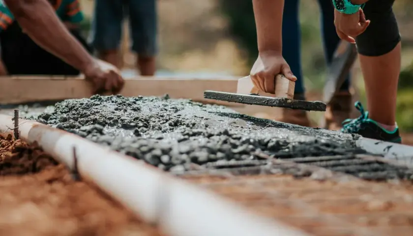 Pracownicy wyrównują świeży beton B20. Cena za m3 jest kluczowa przy planowaniu budowy.