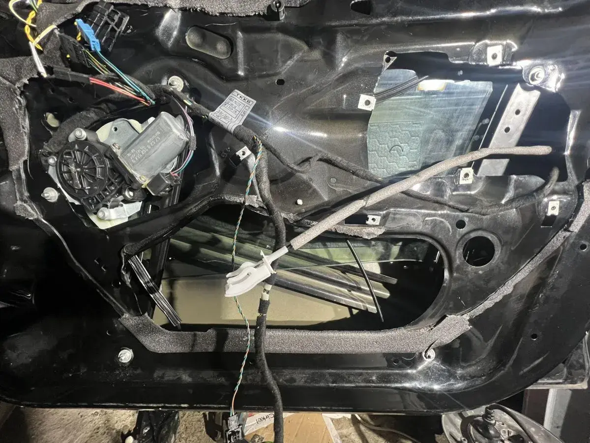 Wnętrze drzwi BMW E46 z widocznym mechanizmem podnoszenia szyby i przewodami.