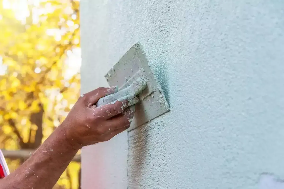 Ręka fachowca wygładza tynk silikonowy. Czas na zacarcie tynku zależy od warunków, ale efekt końcowy jest piękny.