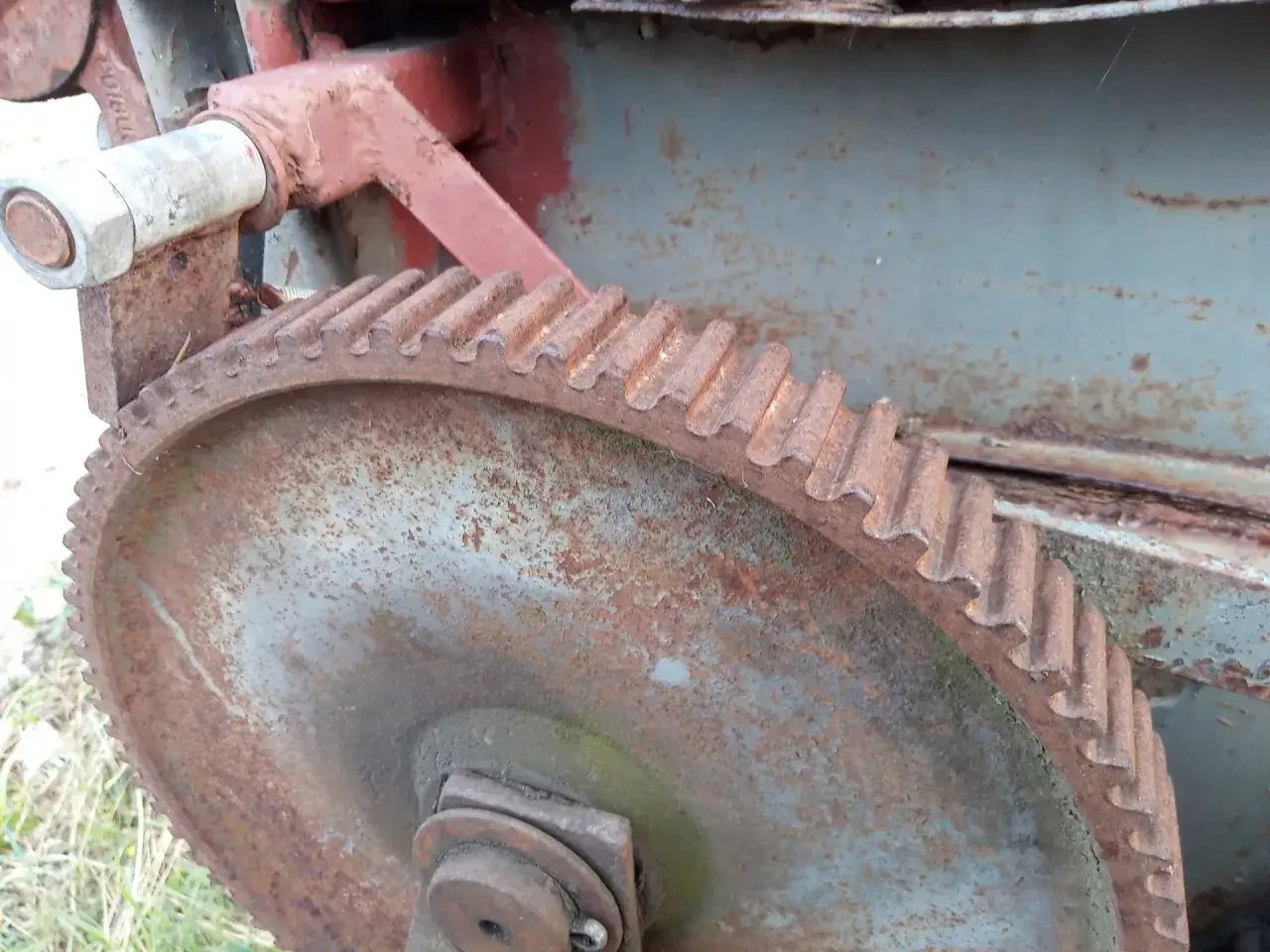 Zardzewiałe koło zębate i mechanizm posuwu rozrzutnika obornika.