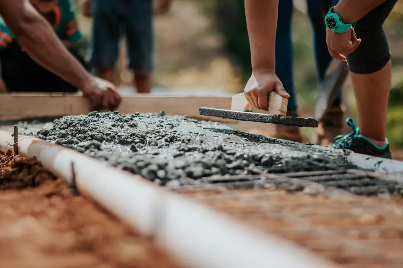 Pracownicy wyrównują świeży beton B20. Cena za m3 jest kluczowa przy planowaniu budowy.