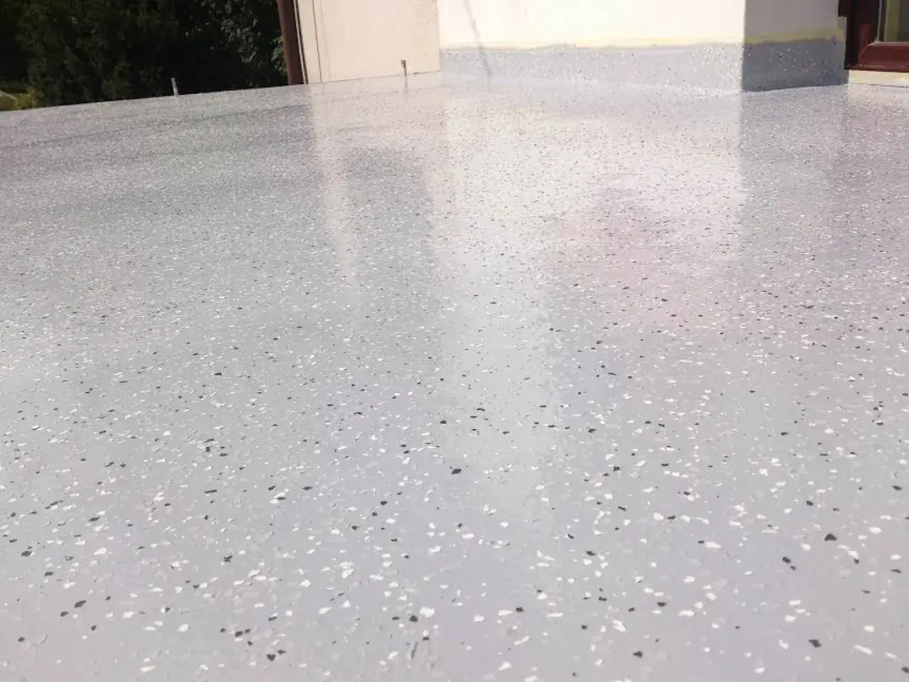 Nowoczesny kamienny dywan koszt 1m2. Jasnoszara posadzka z drobnymi, kolorowymi płatkami, idealna na taras lub balkon.