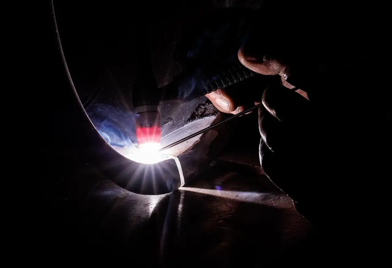 Precyzyjne spawanie aluminium migomatem. Jasny łuk spawalniczy rozświetla ciemność, tworząc iskrzące połączenie.