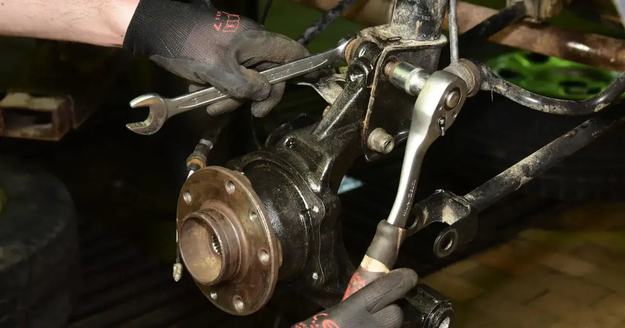 Mechanik wymienia łożysko w kole, używając kluczy. Sprawdź wymiana łożyska w kole cena.