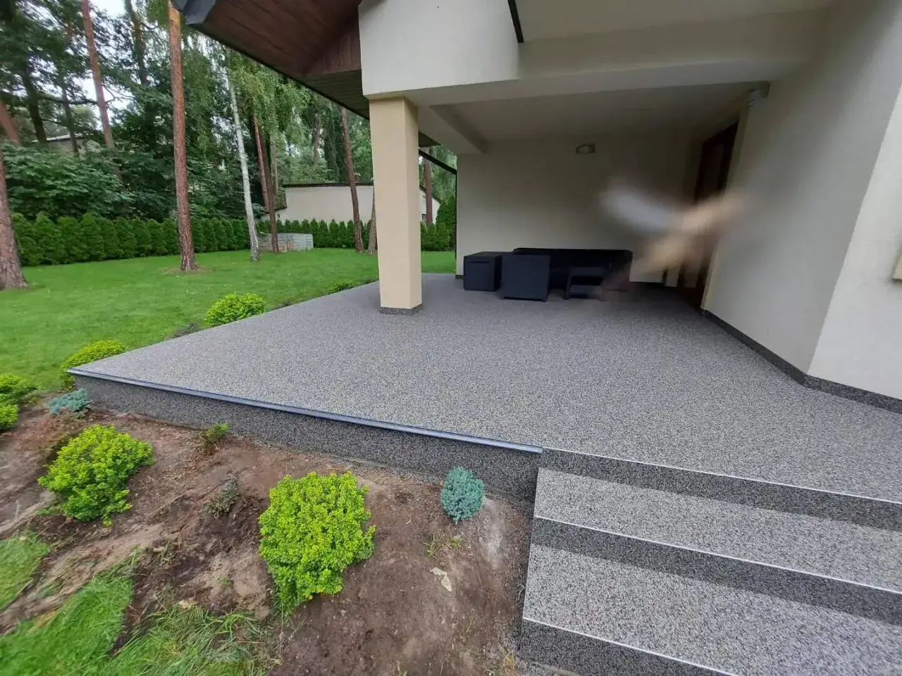 Nowoczesny kamienny dywan koszt 1m2 to eleganckie wykończenie tarasu i schodów, otoczone zielenią.
