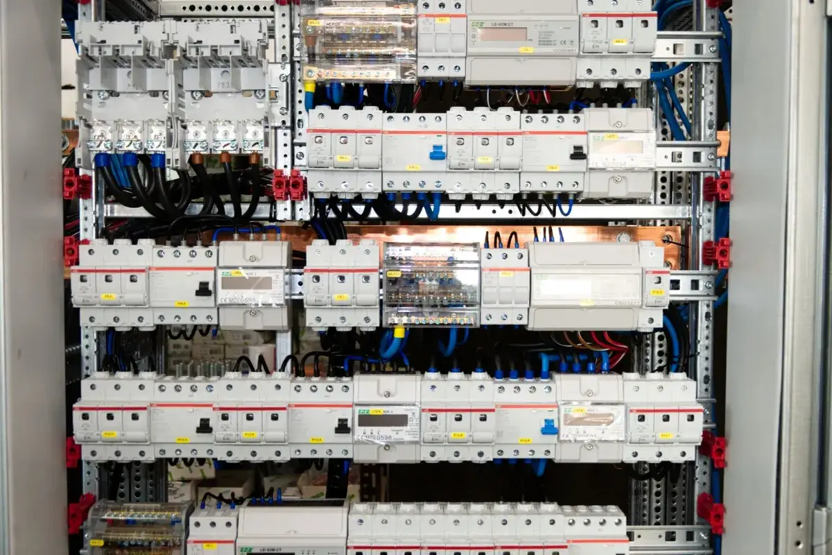 Panel elektryczny z licznymi wyłącznikami, zabezpieczeniami i przewodami. Widać moduły IP20, które zapewniają bezpieczeństwo.