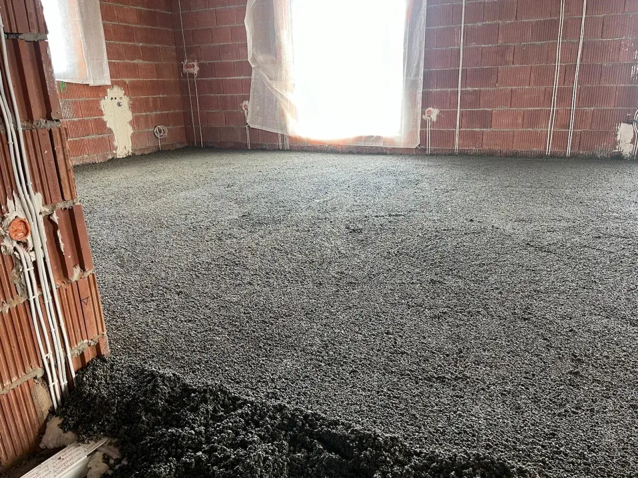 Świeżo wylana wylewka styrobetonowa na podłodze w budowie. Sprawdź, jaka jest wylewka styrobeton cena za m2.