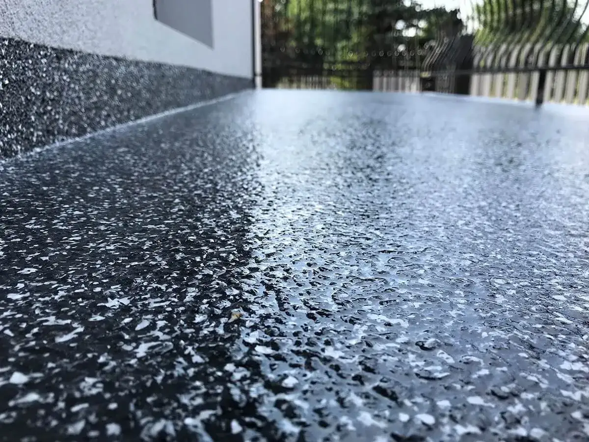 Nowoczesna żywica na balkon cena za metr. Ciemna, błyszcząca powierzchnia z białymi wtrąceniami, idealna na taras.