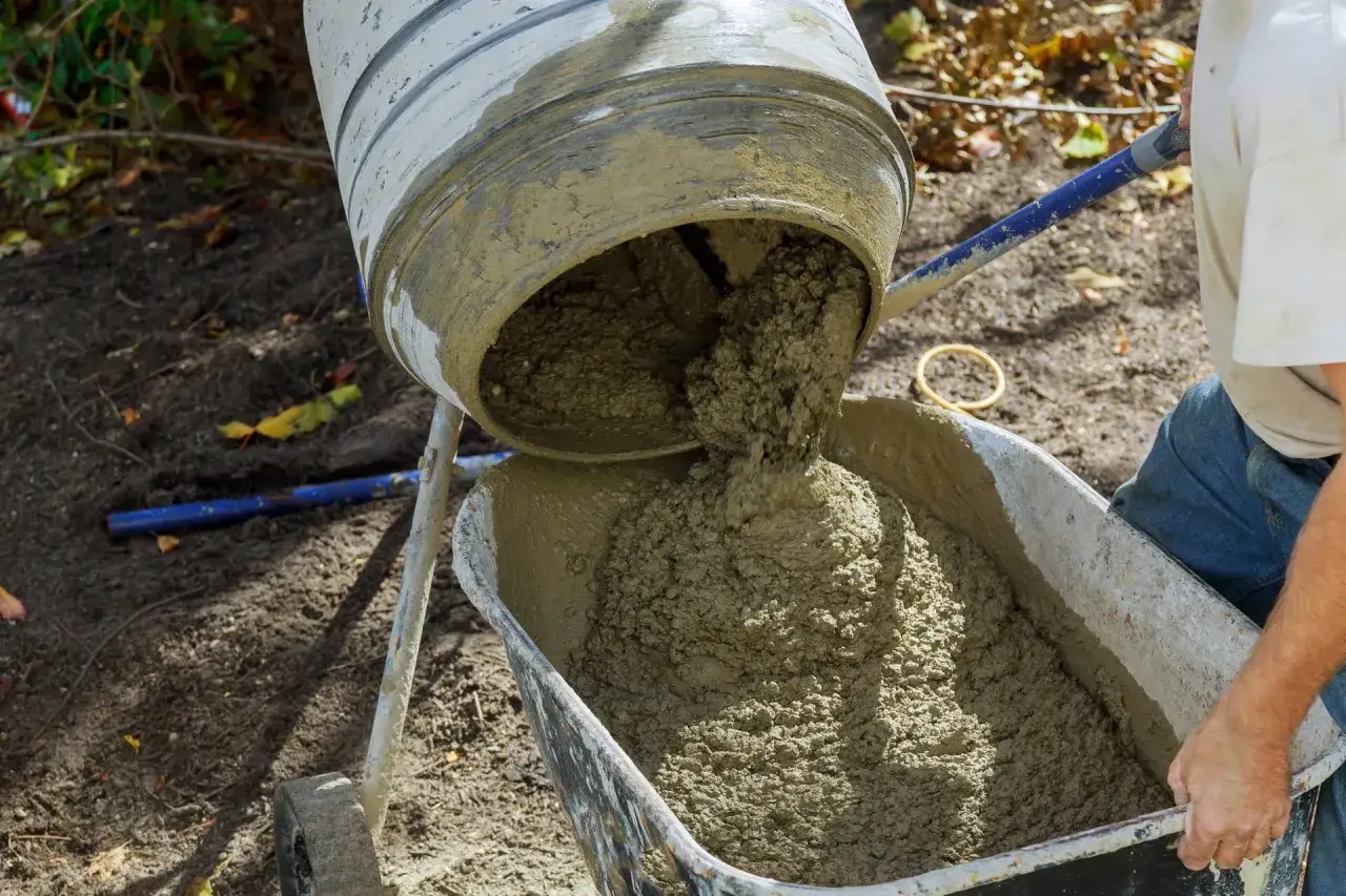 Mieszarka wylewa świeży beton do taczki. Kluczowe są tu proporcje betonu, by uzyskać idealną konsystencję do budowy.