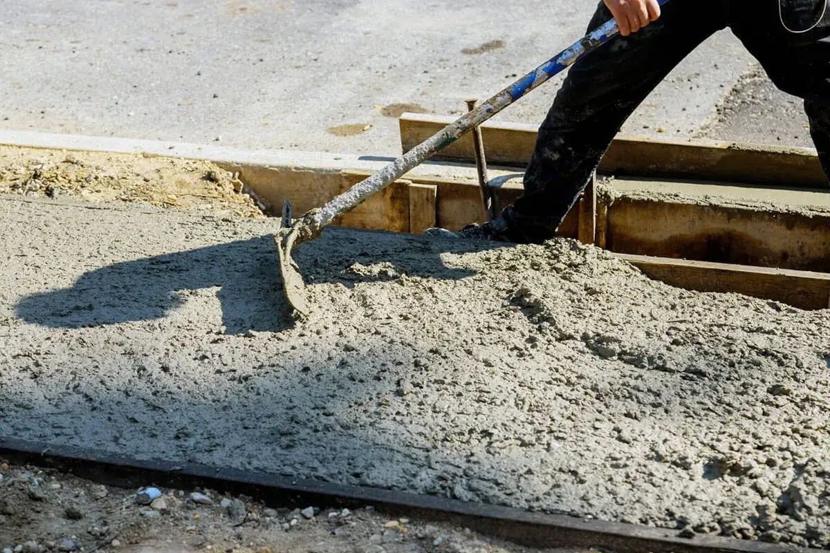 Robotnik rozprowadza świeży beton, pokazując różne rodzaje betonu używane w budownictwie.