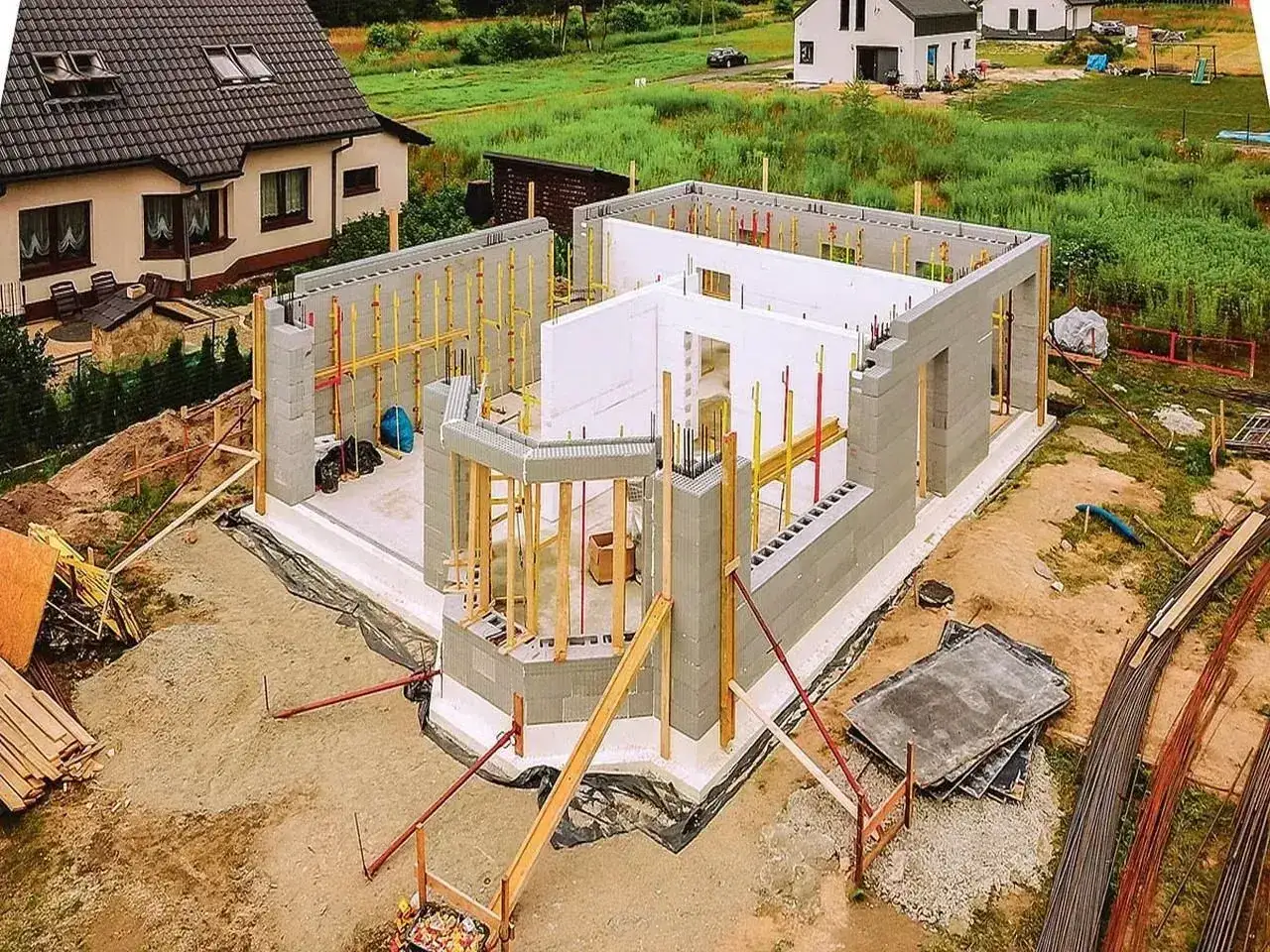 Budowa domu ze styropianu w postępie. Widać fundamenty, ściany z bloczków i elementy konstrukcyjne.
